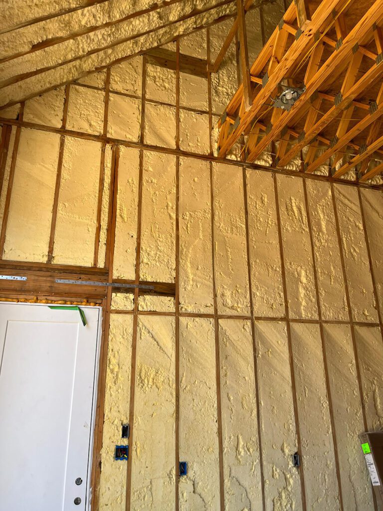 Residential interior with spray foam insulation installed in wall cavities and ceiling joists for a complete airtight seal.