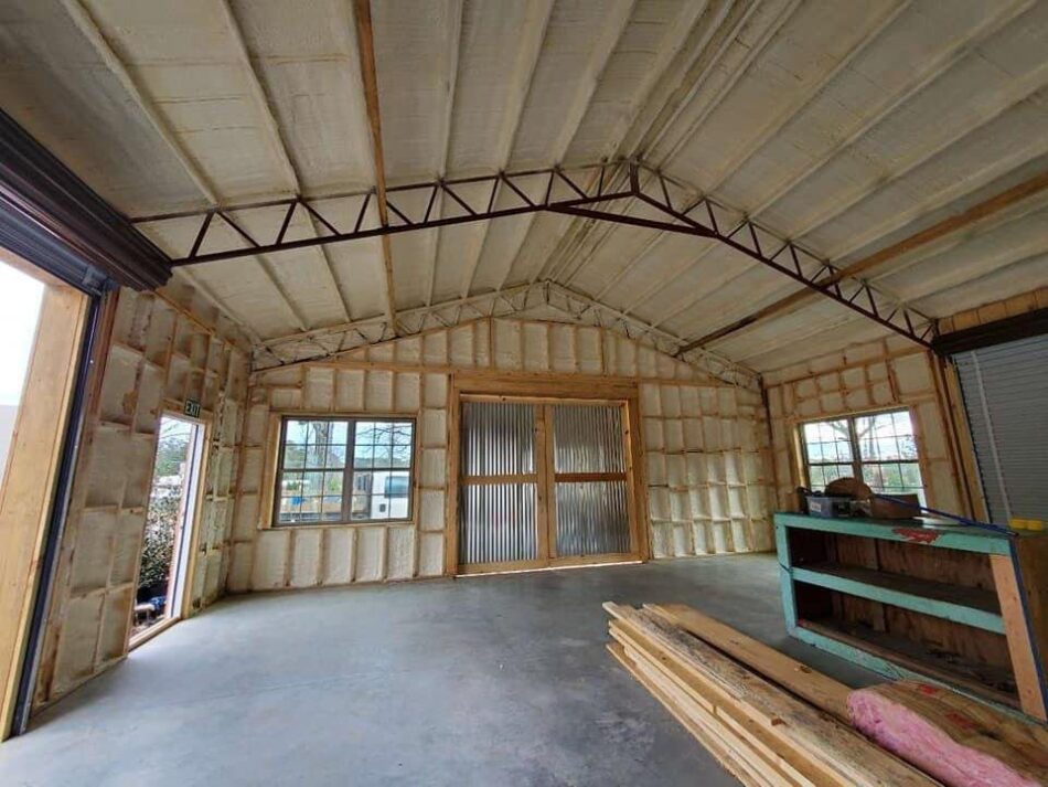 Interior of a large garage or pole barn with spray foam insulation applied to the ceiling and walls for energy efficiency.